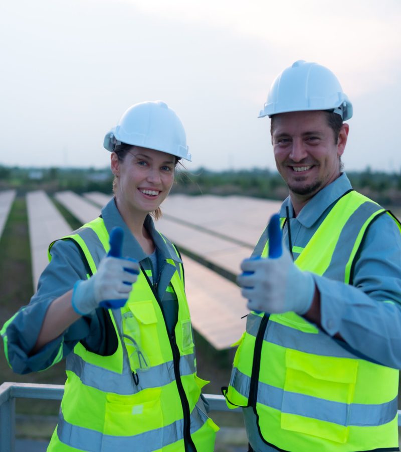 A team of electrical engineers inspecting solar panels in a hundred acres of grass on the rooftop of energy storage station, in the evening after completing the daily work tasks with the setting sun